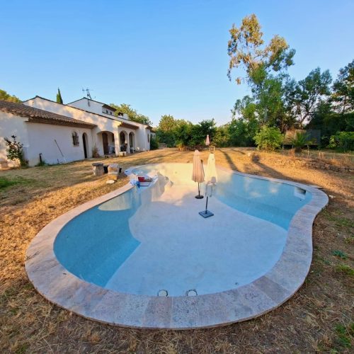Pose de nouvelles margelles et rénovation du revêtement sur une piscine à débordement haut de gamme.